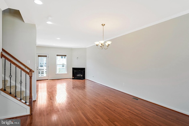 unfurnished living room with stairs, recessed lighting, ornamental molding, a chandelier, and wood finished floors