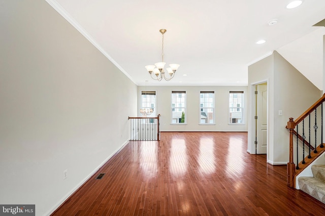 unfurnished living room featuring crown molding, baseboards, a chandelier, wood finished floors, and stairs