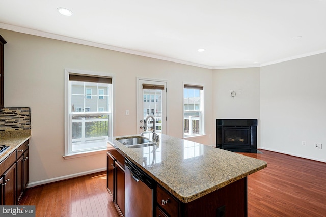 kitchen featuring stainless steel dishwasher, a sink, dark wood-style flooring, crown molding, and baseboards