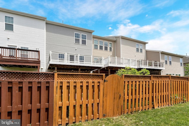 rear view of house with a fenced backyard and a gate
