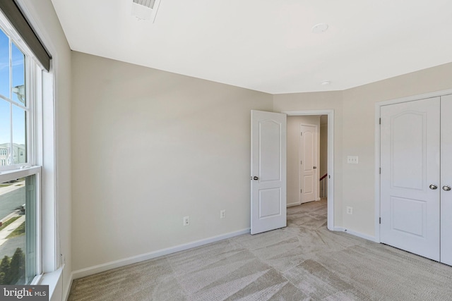 unfurnished bedroom with light carpet, baseboards, and a closet
