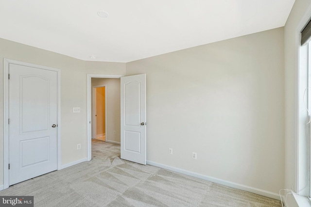 unfurnished bedroom with baseboards and light carpet