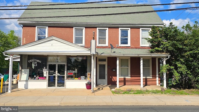 multi unit property featuring french doors, brick siding, a porch, and a shingled roof