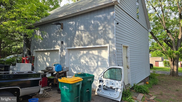 view of side of home with a garage and a shingled roof
