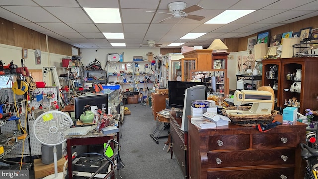 miscellaneous room with ceiling fan, carpet floors, a drop ceiling, and wooden walls