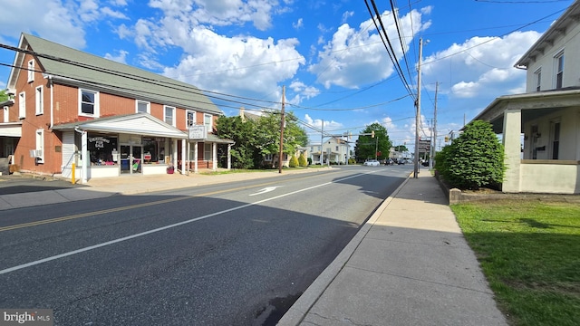 view of asphalt road featuring sidewalks, curbs, and street lights