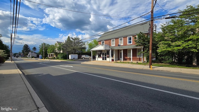 view of asphalt street featuring sidewalks, curbs, and street lighting