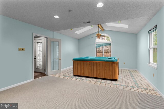 kitchen featuring a skylight, lofted ceiling, baseboards, ceiling fan, and recessed lighting