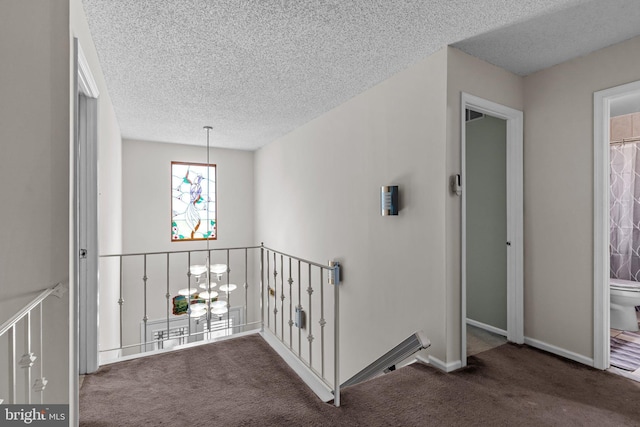 hallway featuring an upstairs landing, carpet floors, a textured ceiling, baseboards, and a chandelier