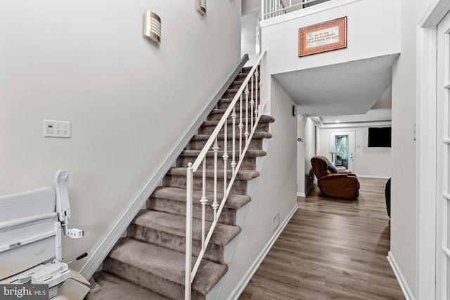 staircase featuring wood finished floors and baseboards