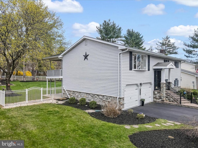 view of side of property featuring stone siding, an attached garage, and asphalt driveway