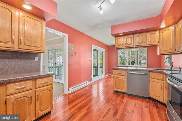 kitchen featuring stainless steel appliances, a baseboard radiator, a sink, and wood finished floors
