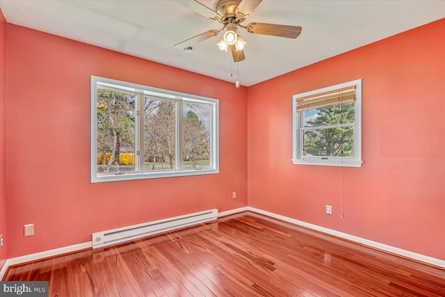 unfurnished room with a baseboard heating unit, baseboards, wood-type flooring, and a ceiling fan