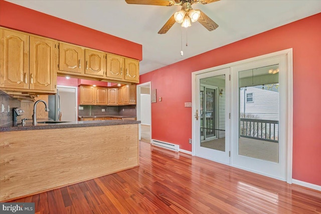 kitchen featuring baseboard heating, decorative backsplash, baseboards, and ceiling fan