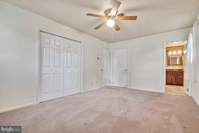 unfurnished bedroom with light carpet, baseboards, ceiling fan, and ensuite bath