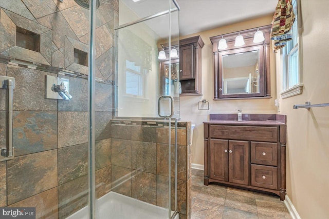 full bathroom with baseboards, a stall shower, vanity, and stone finish flooring