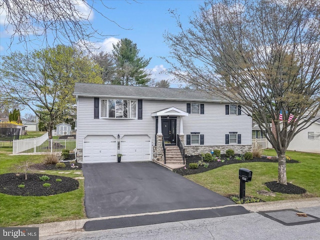 split foyer home with asphalt driveway, stone siding, and an attached garage