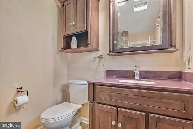 bathroom with toilet, vanity, and baseboards