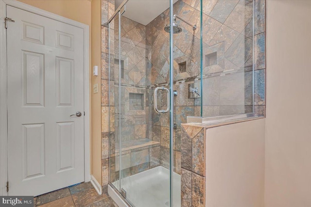 bathroom featuring a stall shower, baseboards, and stone finish floors