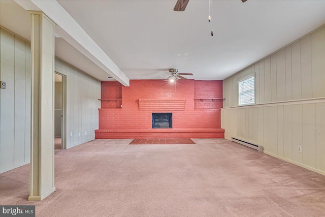 unfurnished living room with ceiling fan, baseboard heating, carpet floors, a fireplace, and wood walls
