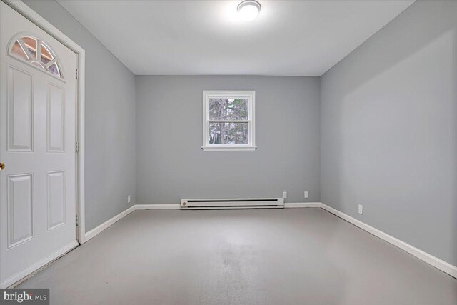 empty room with a baseboard heating unit, baseboards, and finished concrete flooring
