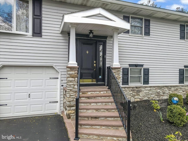 property entrance with stone siding and an attached garage