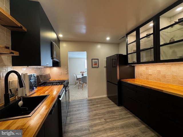 kitchen with wooden counters, dark cabinetry, range with gas cooktop, a sink, and recessed lighting