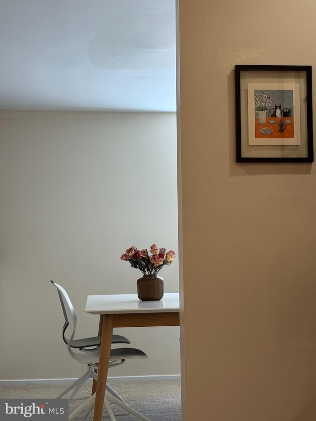 detailed view of a desk, carpet flooring, and baseboards