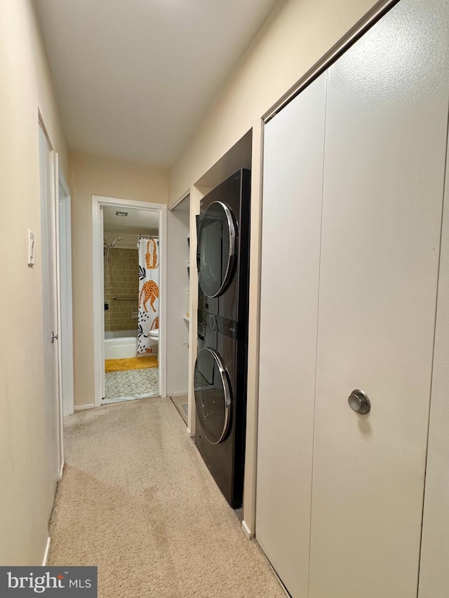 laundry area featuring stacked washing machine and dryer, carpet floors, and baseboards