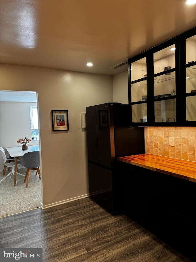 kitchen with backsplash, dark wood finished floors, baseboards, freestanding refrigerator, and wood counters