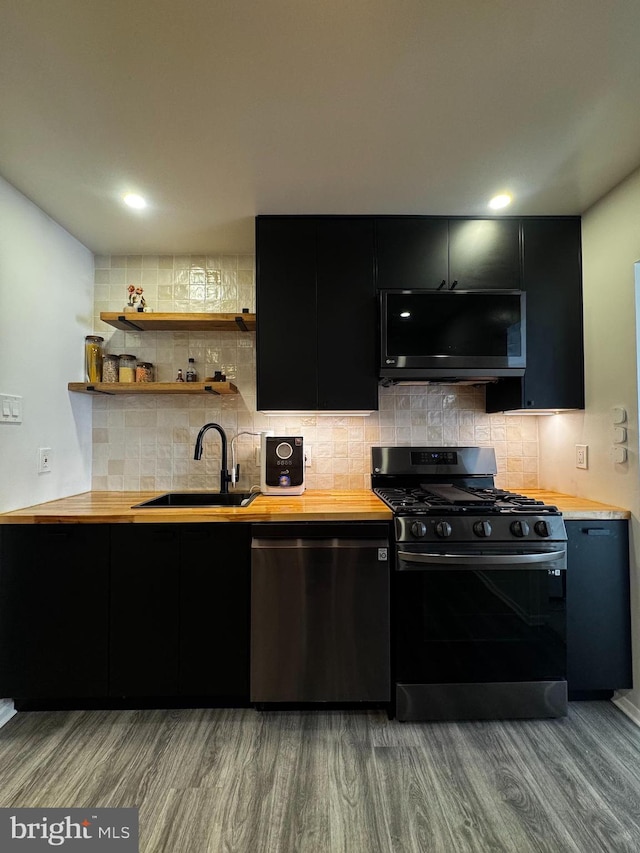 kitchen with dishwasher, gas range, dark cabinetry, and a sink