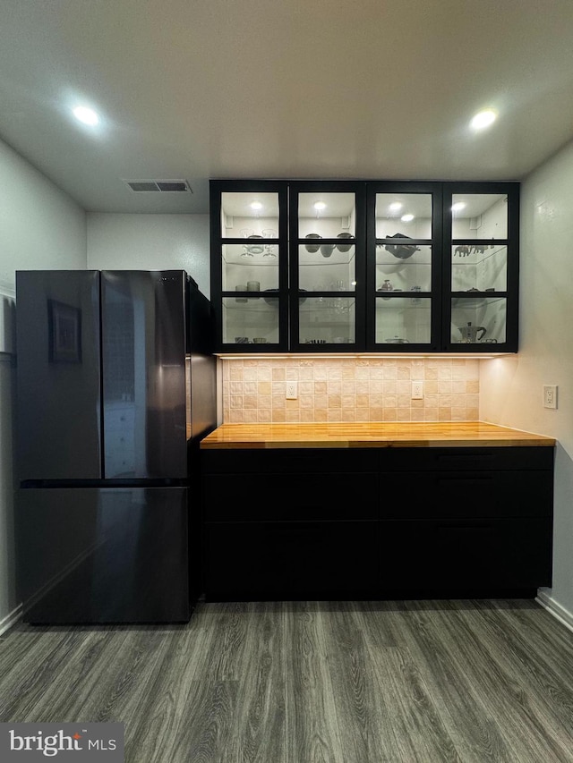 kitchen with freestanding refrigerator, dark wood-type flooring, backsplash, glass insert cabinets, and recessed lighting