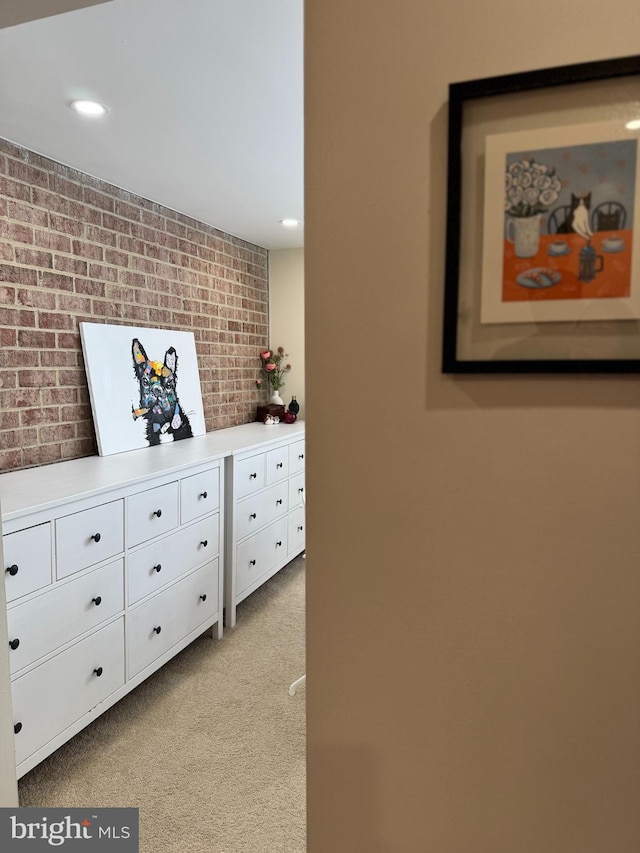 hallway with brick wall, recessed lighting, and light colored carpet