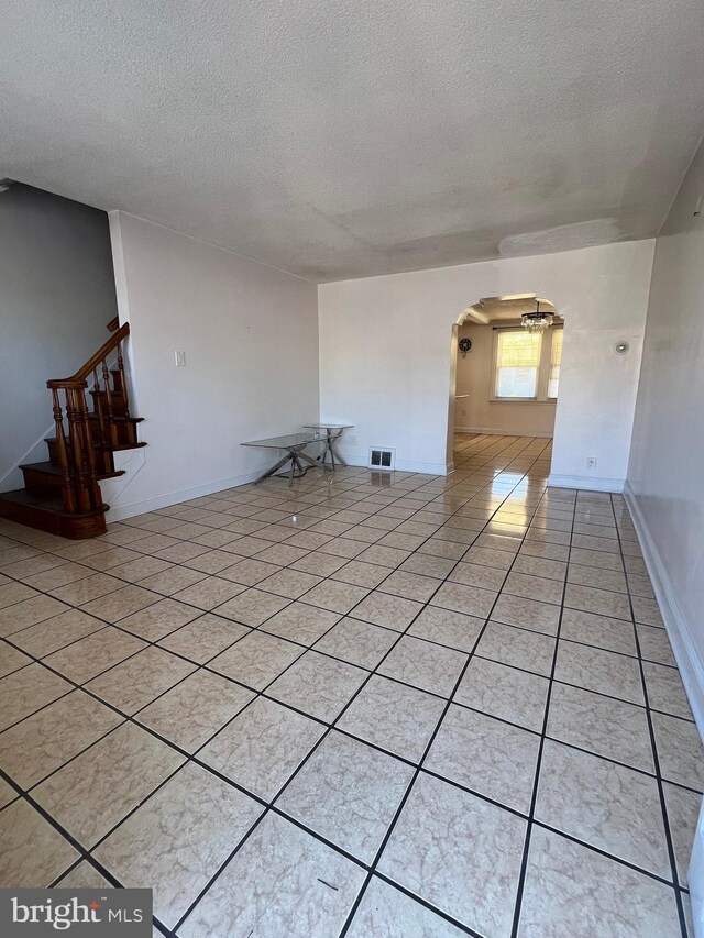 4126 I St, Philadelphia, PA 19124 - spare room with arched walkways, a textured ceiling, stairway, and light tile patterned flooring