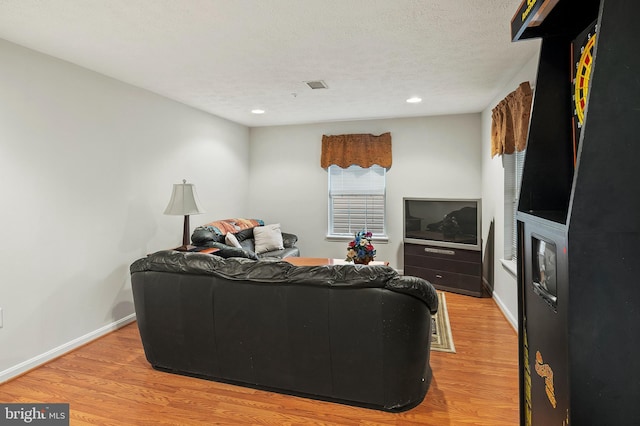 living room featuring light wood-style floors, recessed lighting, baseboards, and a textured ceiling