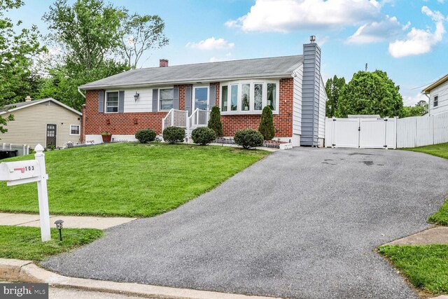 view of front of property featuring a gate, brick siding, a chimney, and driveway