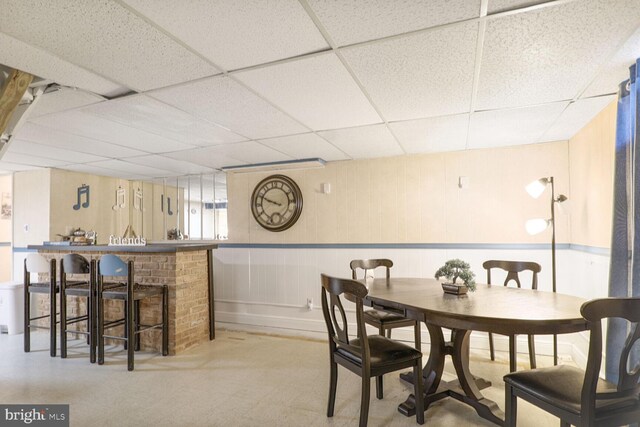 dining space with a drop ceiling and a decorative wall