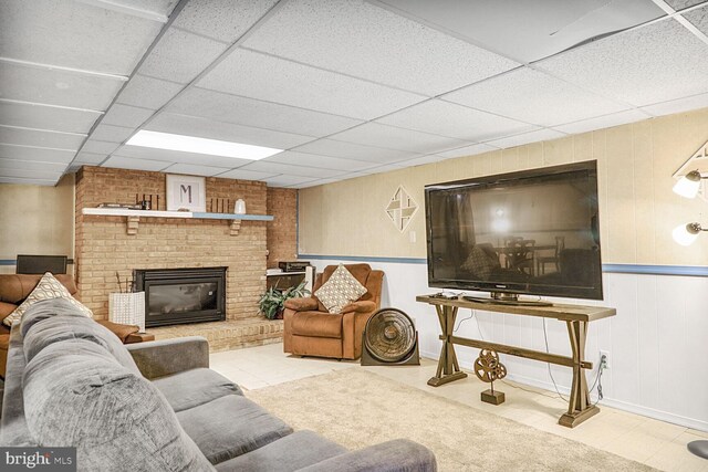 living room featuring a fireplace, tile patterned floors, baseboards, and a paneled ceiling
