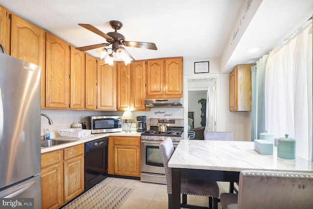 kitchen with stainless steel appliances, under cabinet range hood, a sink, ceiling fan, and light tile patterned flooring