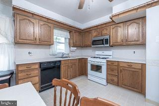 kitchen with gas range gas stove, stainless steel microwave, black dishwasher, ceiling fan, and light countertops