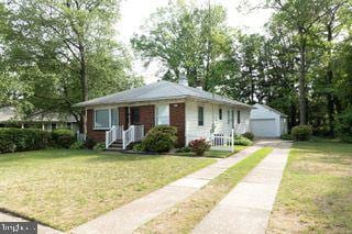bungalow-style home with an outdoor structure, a front yard, driveway, and a garage