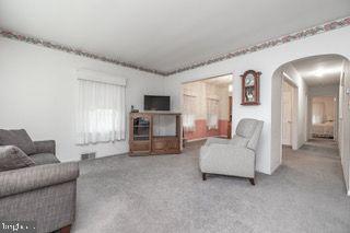 living room with arched walkways and carpet floors