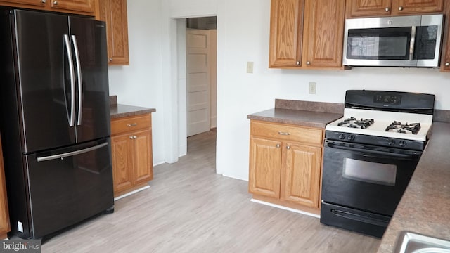 2236 Linden Ave, Baltimore, MD 21217 - kitchen with freestanding refrigerator, stainless steel microwave, gas range, light wood-type flooring, and dark countertops