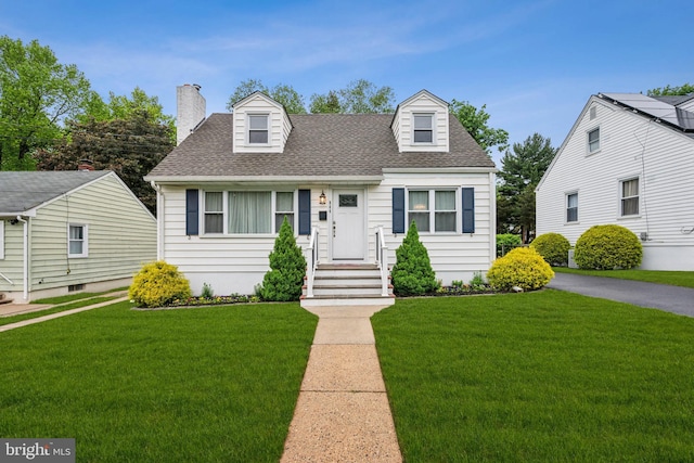 cape cod home with a front lawn, a shingled roof, and a chimney
