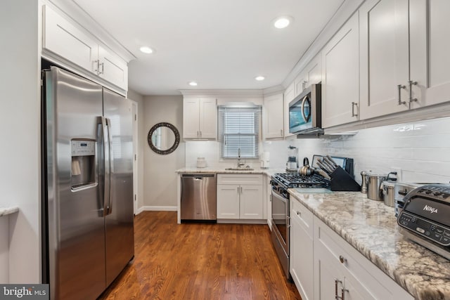 kitchen with appliances with stainless steel finishes, a sink, white cabinets, dark wood-style floors, and recessed lighting