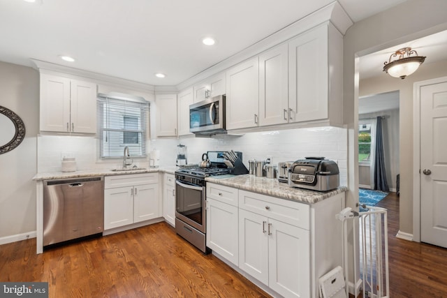 kitchen with stainless steel appliances, a sink, decorative backsplash, white cabinets, and recessed lighting