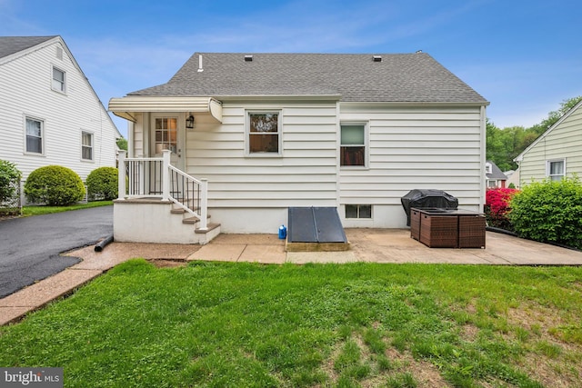 rear view of house featuring a yard, a patio, and a shingled roof