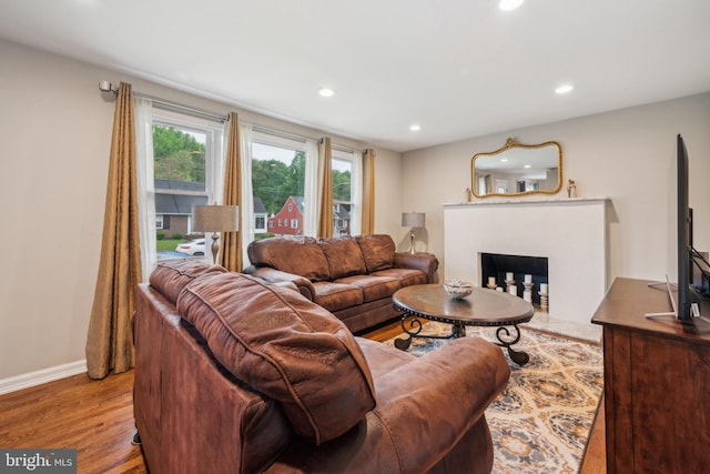 living room with a fireplace, recessed lighting, wood finished floors, and baseboards