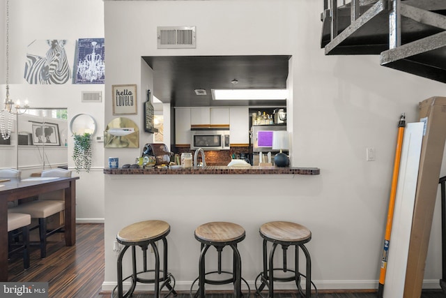 1019 Summerglenn Ct Unit 7-302, Bowie, MD 20721 - kitchen featuring stainless steel microwave, a kitchen bar, baseboards, and dark wood-style flooring
