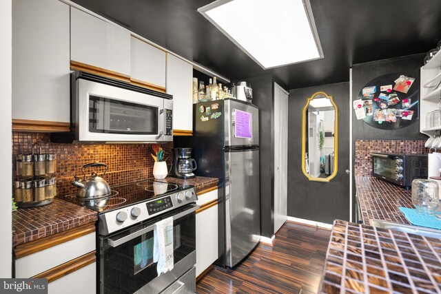 1019 Summerglenn Ct Unit 7-302, Bowie, MD 20721 - kitchen with stainless steel appliances, dark countertops, dark wood-style floors, white cabinets, and decorative backsplash